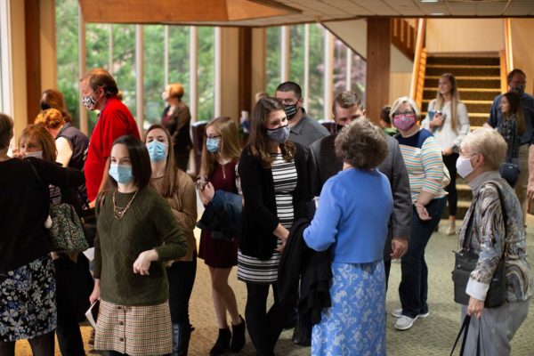 People wearing masks mingle in the church lobby