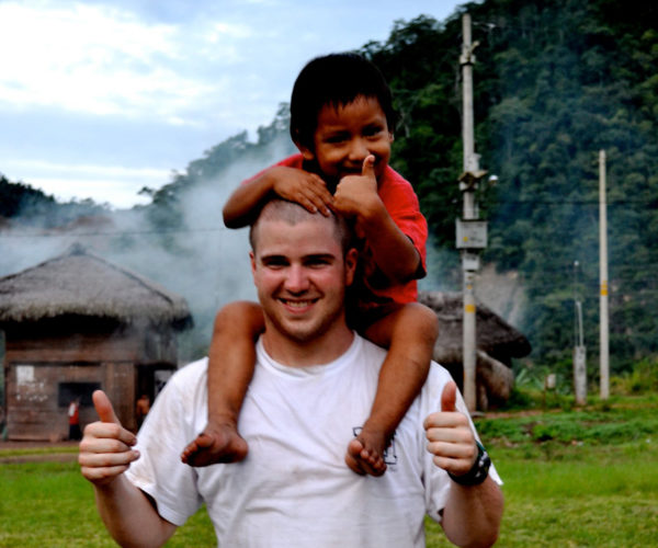A man smiles with a young child on his shoulders